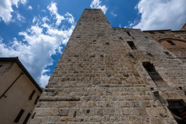 Torre dei Cugnanesi 'nin alçak açılı görüntüsü, San Gimignano' da yaz bulutlarının altında bir ortaçağ taş kule evi..