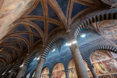 San Gimignano, İtalya - 22 Temmuz 2025: Çizgili Roma kemerleri ve 14. yüzyıl freskleriyle donatılmış Gotik kasalar Collegiata di San Gimignano 'da.