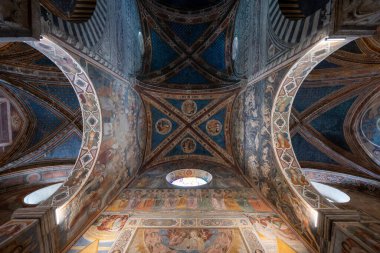 San Gimignano, İtalya - 22 Temmuz 2025: Romanesque Duomo di San Gimignano 'nun freskli mahzeni ve kemerlerinin iç görünümü, zengin bir şekilde boyanmış İncil sahneleri.