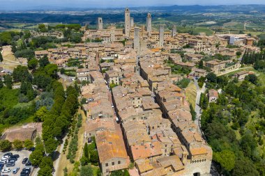 San Gimignanos ortaçağ kuleleri ve Toskana kırsalıyla çevrili taş çatıların havadan görünüşü, eski bir 13. yüzyıl ticaret merkezi..
