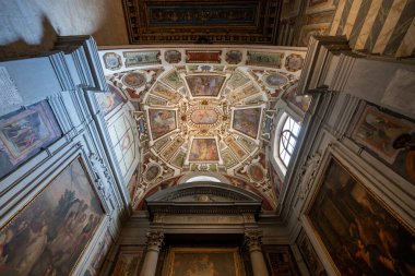 Volterra, İtalya - 21 Temmuz 2025: Tuscany, İtalya 'daki Volterra Katedrali içindeki zengin freskli Rönesans kasasının ve yan şapellerin düşük açılı görüntüsü.