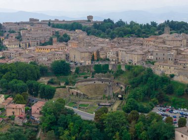 Aerial view of the 1st century BC Roman Theatre ruins below the medieval hilltop town of Volterra in Tuscany.