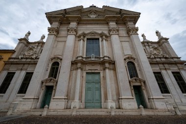 Mantuas Cattedrale di San Pietro 'nun Barok taş cephesinin alçak açılı görüntüsü, Korint pilastlarını, heykellerini ve merkez portalını gösteriyor..