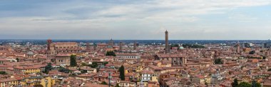 Bolognas 'ın panoramik manzarası kırmızı kiremitli çatılar ve Asinelli, Garisenda ve San Petronio Bazilikası gibi ortaçağ kuleleri bulutlu yaz gökyüzü altında.
