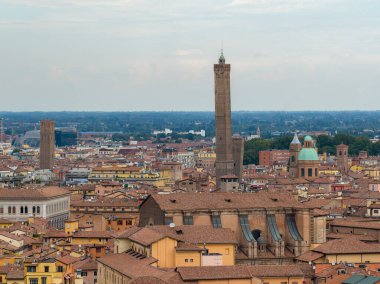 Bulutlu bir yaz gününde, terasotta çatılarının ve tarihi kiliselerin üzerinde yükselen tuğlalı Asinelli Kulesi ile ortaçağ Bolonya 'sına bakın..