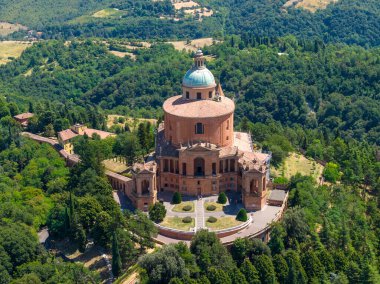 San Luca Leydisinin Barok Tapınağı 'nın havadan görünüşü Monte della Guardia' nın tepesinde, Bologna yakınlarındaki ağaçlık tepelerle çevrili.