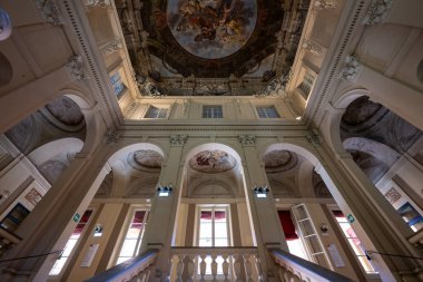 Bologna, İtalya - 23 Temmuz 2025: Bologna 'daki Palazzo Ercolani' nin iç mimarisi, Barok büyük merdivenleri, kemerler, sıva dekorasyonu ve dramatik tavan freski.