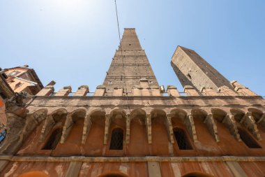 Ortaçağ Asinelli 'sinin alçak açılı görüntüsü ve eğimli Garisenda tuğla kuleleri Bologna' daki iri yarı bir perdenin üzerinde yükseliyor..