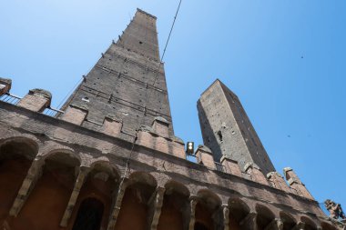 Orta Çağ Asinelli 'sinin alçak açılı görüntüsü ve açık gökyüzünün altında orta Bolonya' daki atari salonlarının üzerinde yükselen eğimli Garisenda tuğla kuleleri.