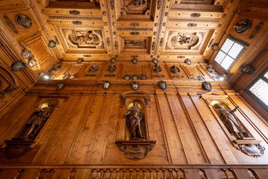 Bologna, İtalya - 23 Temmuz 2025: Süslü ahşap duvar ve heykel ve arşivli tavan Archiginnasio Belediye Kütüphanesi 'nin içinde kraliyet kalkanları, Bolonya Üniversitesi' nin tarihi merkezi.