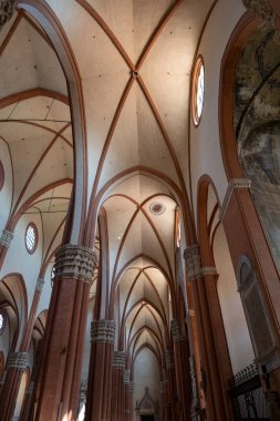 Bologna, İtalya - 23 Temmuz 2025: Gotik kasalar ve 14. yüzyıl San Petronio Bazilikası içindeki yüksek tuğlalı rıhtımlar, rahibin pencereleriyle aydınlatıldı.