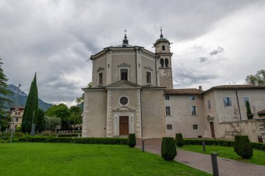 Santa Maria Barok Kilisesi 'nin dışı Riva del Garda' da, bulutlu yaz gökyüzünün altında çimlerin üzerinde görüldü..
