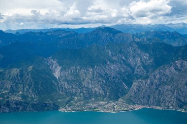 Garda Gölü 'ndeki Limon Konsolosu Garda' nın yüksek hava manzarası. Dik kireçtaşı uçurumları ve yaz bulutlarının altındaki orman zirveleriyle destekleniyor..
