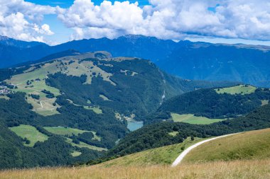 Malcesine tepesindeki Baldo Dağı 'nın çayırları ve ormanları boyunca yaz manzarası, Adige Alpleri' ndeki küçük bir dağlık göle bakıyor..