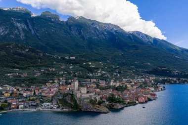 Castello Scaligero ve ortaçağ Malcesine 'nin havadan görünüşü yaz ışığında dik Monte Baldo yamaçlarının altında Garda Gölü boyunca yoğun bir şekilde inşa edilmiştir..