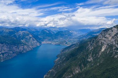Riva del Garda yakınlarındaki Garda Gölü 'nün kuzey havzasının yüksek hava manzarası dik orman kayalıkları ve uzak Alpler tarafından çerçevelenmiştir..