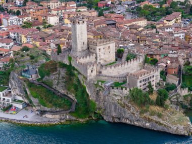 Ortaçağ Castello Scaligero ve güçlendirilmiş kireçtaşı duvarlarının havadan görünüşü Malcesine, İtalya 'daki Garda Gölü üzerindeki uçurumlara tünemişti..
