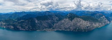 Garda Gölü 'nün yüksek hava manzarası Limon Sul Garda üzerindeki dik kireçtaşı kayalıklarını ve dramatik yaz bulutlarının altındaki Prealpleri gösteriyor..