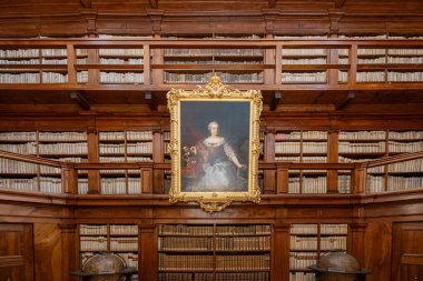 Mantua, İtalya - 26 Temmuz 2025: Mantua 'da 18. yüzyıl Biblioteca Teresiana' sının ahşap panelli okuma odası, tabandan tavana raflar ve merkezi bir barok portresi.