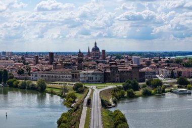 Aerial view of Mantua across its artificial lakes, showing the Palazzo Ducale complex, medieval brick towers and SantAndrea dome.