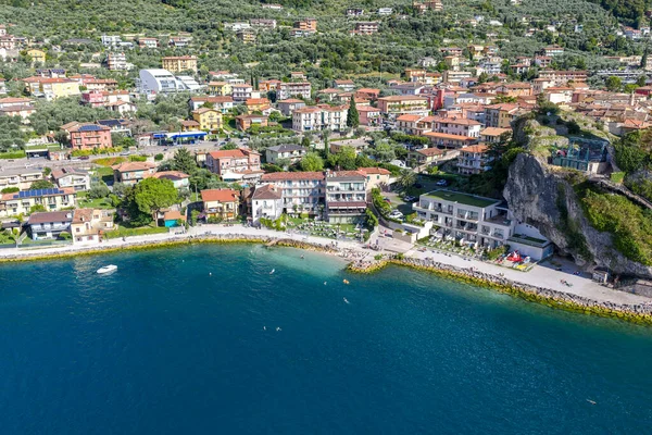 Malcesine 'deki Garda Gölü' ndeki Paina Plajı 'nın havadan görünüşü çakıl taşlı kıyı şeridi, sahil otelleri, liman ve dik kayalık yamaçları gösteriyor..