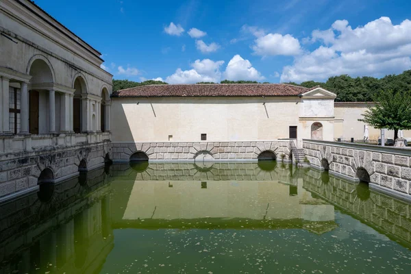 Mantua 'daki Palazzo Te' nin Rönesans avlusunda taş kemerler, sıva duvarlar ve yansıtıcı hendekler var..
