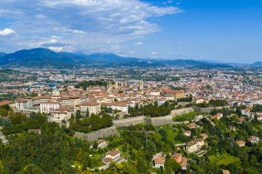 16. yüzyıl Venedik duvarları, yoğun terasotta çatıları ve yaz ışığında Lombardy Alplerine karşı yeşil tepeleri olan Bergamo Alta 'nın hava manzarası..