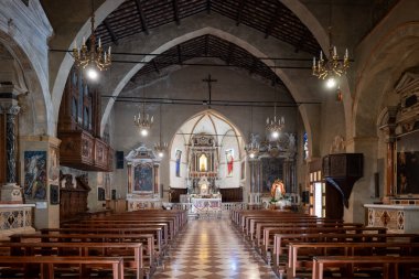 Sirmione, Italy - Jul 29, 2025: Central nave of Santa Maria Maggiore in Sirmione, showing wooden truss ceiling, frescoed chapels, marble altar and checkered tile floor.