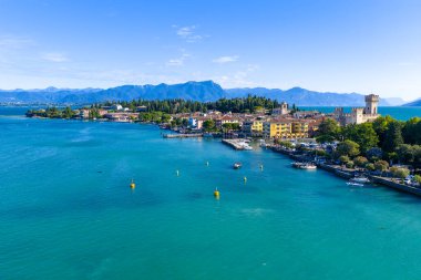 Garda Gölü 'ndeki Sirmione Yarımadası' nın hava manzarası göldeki tarihi binaları, marinayı ve yaz ışığında uzak Alp eteklerini gösteriyor..