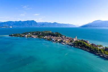 Garda Gölü 'ne uzanan dar Sirmione yarımadasının yüksek hava manzarası, turkuaz su ve uzak Prealplerle çevrili..