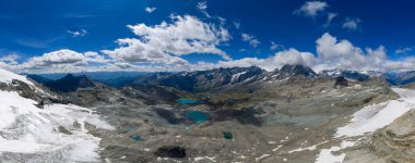 Testa Grigia yakınlarında geniş bir alp manzarası var. Buzul vadileri, kayalık tepeler, kar tarlaları ve turkuaz gölleri parlak bir yaz gölü altında..