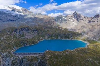 İtalyan Alpleri 'ndeki Valtournenche' nin yukarısındaki Lago Goillet hidroelektrik rezervuarının havadan görünüşü, kayalık zirveler ve yaz sonu kar tarlalarıyla çevrili..