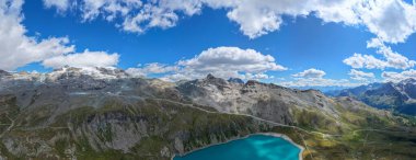 Açık bir yaz gününde Aosta Vadisi 'ndeki Valtournenche' nin yukarısındaki buzullu Alp tepelerinin altındaki Turkuaz Lago Goillet rezervuarının hava manzarası..