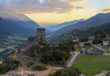 Ortaçağ Castello di Cly, gün batımında alp tepeleriyle çevrelenen İtalya 'nın Aosta Vadisi' nin üzerindeki kayalık bir tepede harabeler..