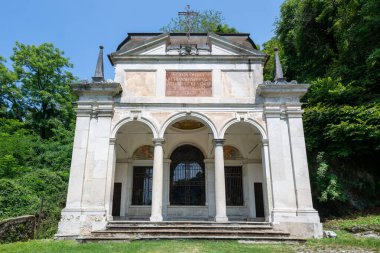 Sacro Monte di Varese 'deki Barok Şapeli X, orman yamaçlarında bulunan kemerli giriş ve Latin yazıtları olan kireçtaşı perisi..