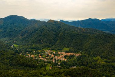 Rasa di Varese 'nin havadan görünüşü, sık ormanlarla çevrili küçük bir dağ köyü ve yaz ışığında yuvarlanan Lombardiya dağları..