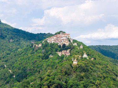İtalya 'nın kuzeyinde, Varese yakınlarında, yoğun Prealpin ormanlarıyla çevrili, yoğun bir tepe köyünün hava manzarası yaz bulutlarının altında..