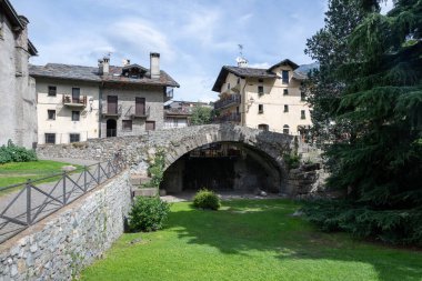 Aosta 'da eski bir taş kemer köprüsü. Kuru bir kanala yayılmış. Geleneksel duvar ustası ve tahta çatı tarzında dağlık köy evleriyle sınırlandırılmış..