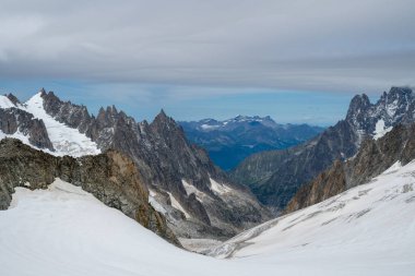 Bir yaz günü Courmayeur 'un yukarısındaki Mont Blanc kalabalığında Pointe Helbronner' ın buzlu yamaçları ve sivri granit tepeleri.