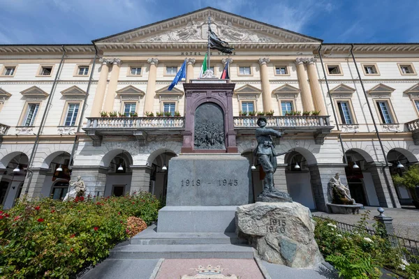 Piazza Chanoux 'daki Neoklasik Aosta Belediye Binası Birinci ve İkinci Dünya Savaşı anıtıyla aydınlık yaz gökyüzü altında.