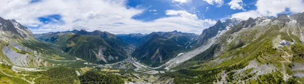 Uçsuz bucaksız dağ vadisinin geniş hava manzarası sarp kayalıklar, yeşil yamaçlar, kıvrımlı nehir yatakları ve dağınık bulutlar..