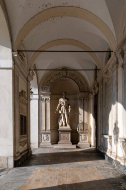 Torino, İtalya - 9 Ağustos 2025: Bir devlet adamının mermer heykeli Torino Belediye Binası 'ndaki kubbeli bir barok kapısının altında, öğleden sonra ışıklarıyla aydınlandı.