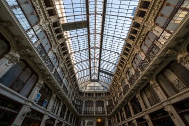Torino, İtalya - 9 Ağustos 2025: Turin 'deki Galleria Subalpina' nın iç kesimi, 19. yüzyıl sonlarında demircilik balkonları ve mağazaların önünde büyük bir cam tavan penceresi atari salonu.