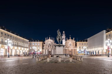 Torino, İtalya - 9 Ağustos 2025: İkiz Barok kiliselerinin çerçevelediği Emmanuel Philibert 'in binicilik heykeli Torino' daki Piazza San Carlo 'nun gece manzarası.