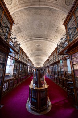 Torino, İtalya - 11 Ağustos 2025: 19. yüzyıldan kalma Torino Kraliyet Kütüphanesi 'nin fıçı kemerli okuma odası, süslü sıva tavanı ve kırmızı halı kaplayan ahşap kitaplıklar.