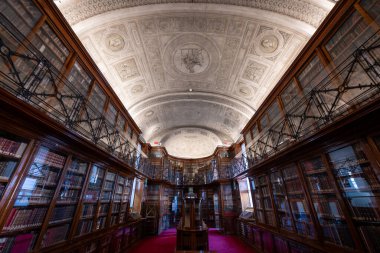 Torino, İtalya - 11 Ağustos 2025: Torino Kraliyet Kütüphanesi okuma odasının içi, süslü tavan, ahşap kitaplıklar ve nadir el yazmalarını barındıran galerileri gösteriyor.