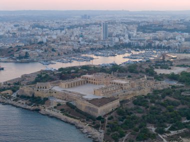Marsamxett Limanı yakınlarındaki Manoel Adası 'ndaki Manoel Kalesi' nin havadan görünüşü, Gzira yakınlarındaki Barok kalelerinin yoğun kentsel kıyı şeridine karşı alacakaranlıkta olduğunu gösteriyor..
