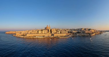 Vallettas kireçtaşı kalelerinden oluşan hava manzarası ve gün batımında Grand Harbour 'un üstündeki kubbeli siluet yarımadadaki güçlendirilmiş Barok şehrini gösteriyor..