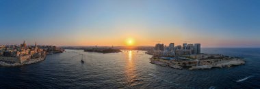 Günbatımında Grand Harbour ve Marsamxett Limanı 'nı çevreleyen Valletta ve modern Sliema gökdelenleri, kireçtaşı kaleleri ve yoğun rıhtım bloklarını gösteriyor..