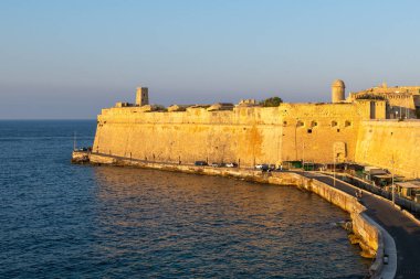 Kireç taşı kale duvarlarının kıyı manzarası ve Malta Valletta, Malta 'nın aşağısındaki Yahudi Sally Limanı, deniz yolu ve sakin Akdeniz' in altın saatinde.